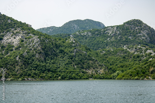 Croup of green mountains around beautiful lake. Landscape on the natural park highlands. Panoramic view on the lake shore. © IhorStore
