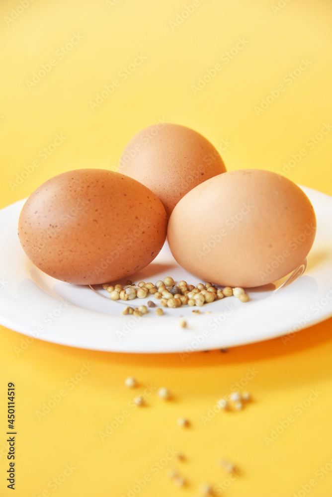 Chicken eggs placed on white plate with some white pepper on color background Chicken eggs placed on white plate with some white pepper on color background