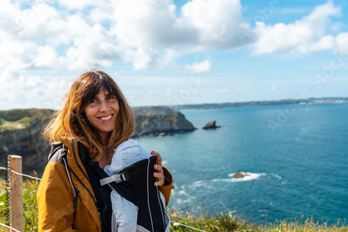 A pretty young woman with her baby on the coastal path next to the Fort des Capucins a rocky, clifftop islet in the town of Roscanvel on the Crozon peninsula in France.