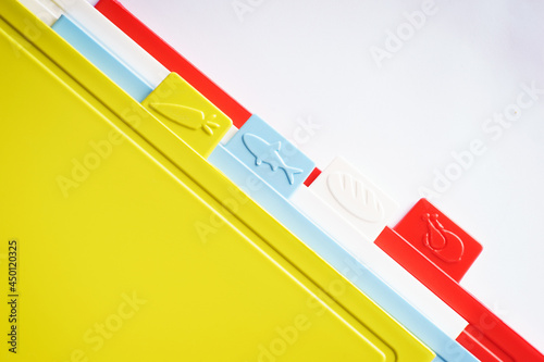 Multicolored bright plastic boards for cutting vegetables, bread, meat and other products on a white background.