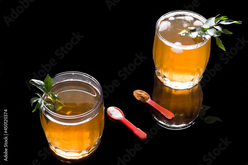 Front view of Kahwa,an Indian Kashmiri green tea made from herbal leaves,saffron and cinnamon. Glasses filled with ice cubes .Sweet,refreshing and healthy golden drink on a black background. photo