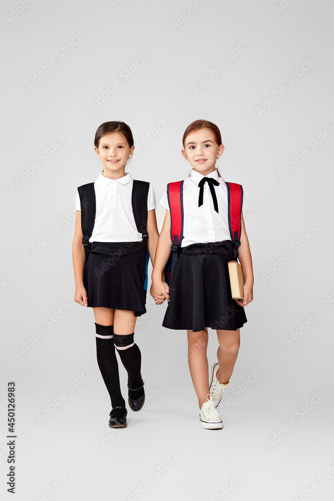 Fototapeta premium two happy little cheerful friends schoolgirls with backpacks