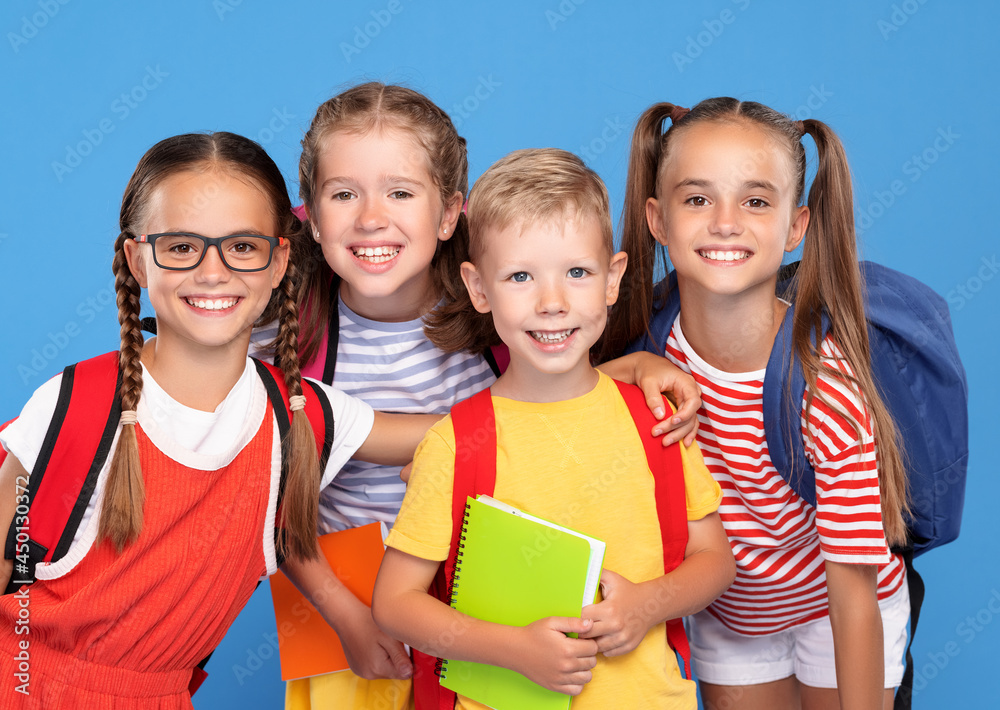 Happy children, girls and boys, standing with backpacks behind and exercise books, smiling at camera Happy children, girls and boys, standing with backpacks behind and exercise books, smiling at camera