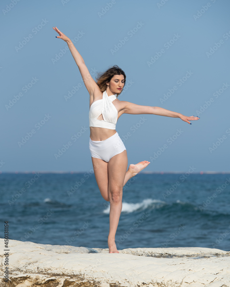 Young woman dancing outdoors on a rocky coast by the ocean Young woman dancing outdoors on a rocky coast by the ocean