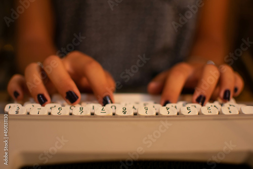 Caucasian teen fingers writing on a retro typewriter close-up.