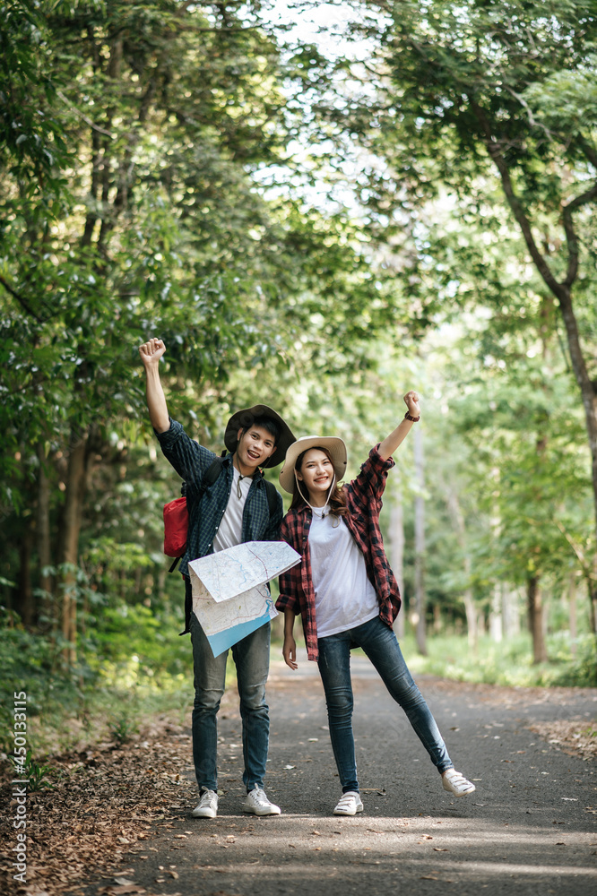 Fototapeta premium Young trekking couple use map while walking on forest trail