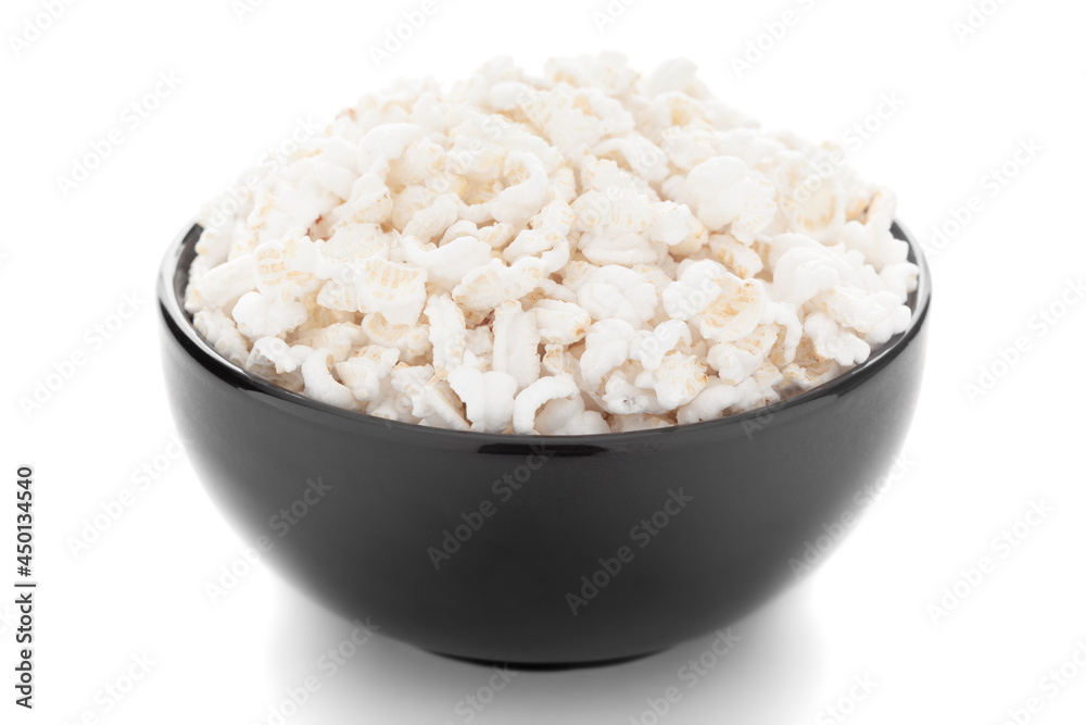 Close-up of organic puffed / roasted rice (kheel or murmura) in a black ceramic bowl over white background. Close-up of organic puffed / roasted rice (kheel or murmura) in a black ceramic bowl over white background.