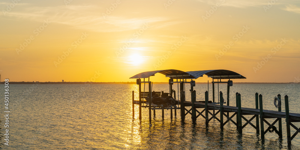 View of a sunset over a wooden pier in Indian River, Florida from the A1A. Wooden pillars of the old pier near the coast as a typical view of Florida
