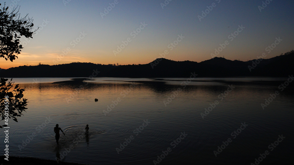 People enjoying a lake fresh water at sunset. Peaceful, relaxing, calm summer vacation.