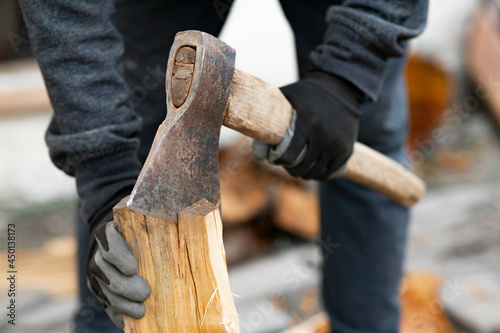 A man is sawing a tree with an ax. a strong man chopping logs with an ax. Firewood chopping process