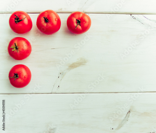 Group of fresh healthy tomatoes on a white wooden background. Additional place for text.
