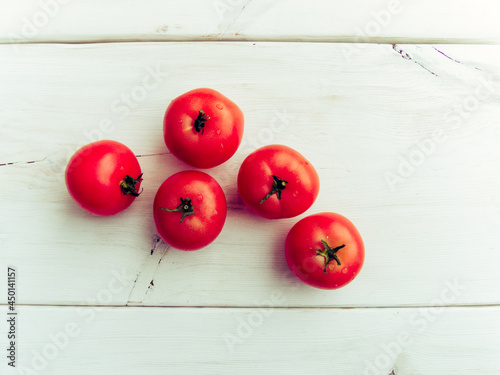 Group of fresh healthy tomatoes on a white wooden background. Additional place for text.