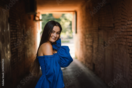 Portrait happy young woman wearing blue dress laughing looking at camera standing on street. Urban background © Анастасія Стягайло