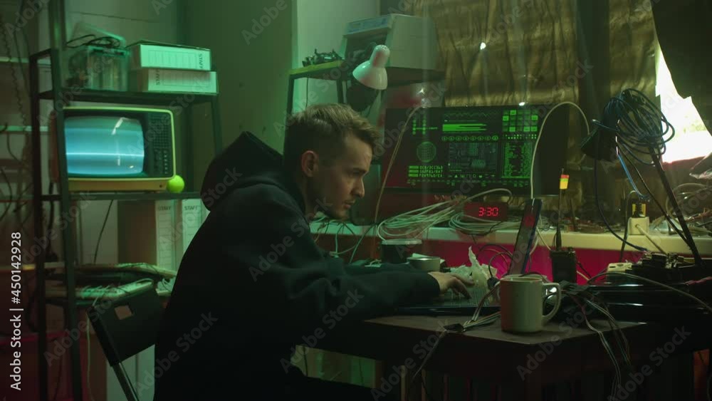 Careful hacker entering room and typing on keyboard, preparing to break password and looking around. Young man criminal stealing information from laptop. Programmer working at night, hacker attack Careful hacker entering room and typing on keyboard, preparing to break password and looking around. Young man criminal stealing information from laptop. Programmer working at night, hacker attack