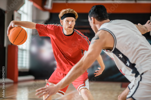 Two young men playing basketball and looking involved
