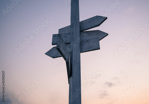 White wooden signpost with a sky during sunset in the background.