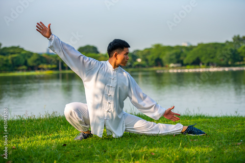 Young man doing TAI CHI exercise in the public park.