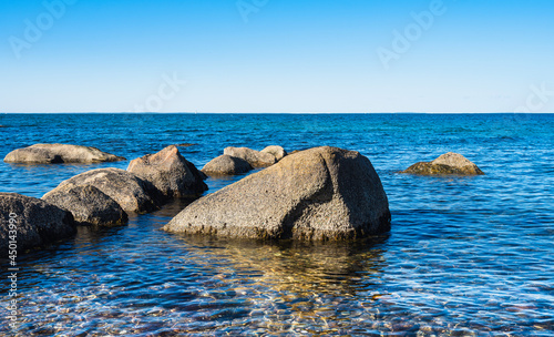 Seascape with glacial rocks in the crystal clear turquoise colored seawater on Cape Cod, Massachusetts.
