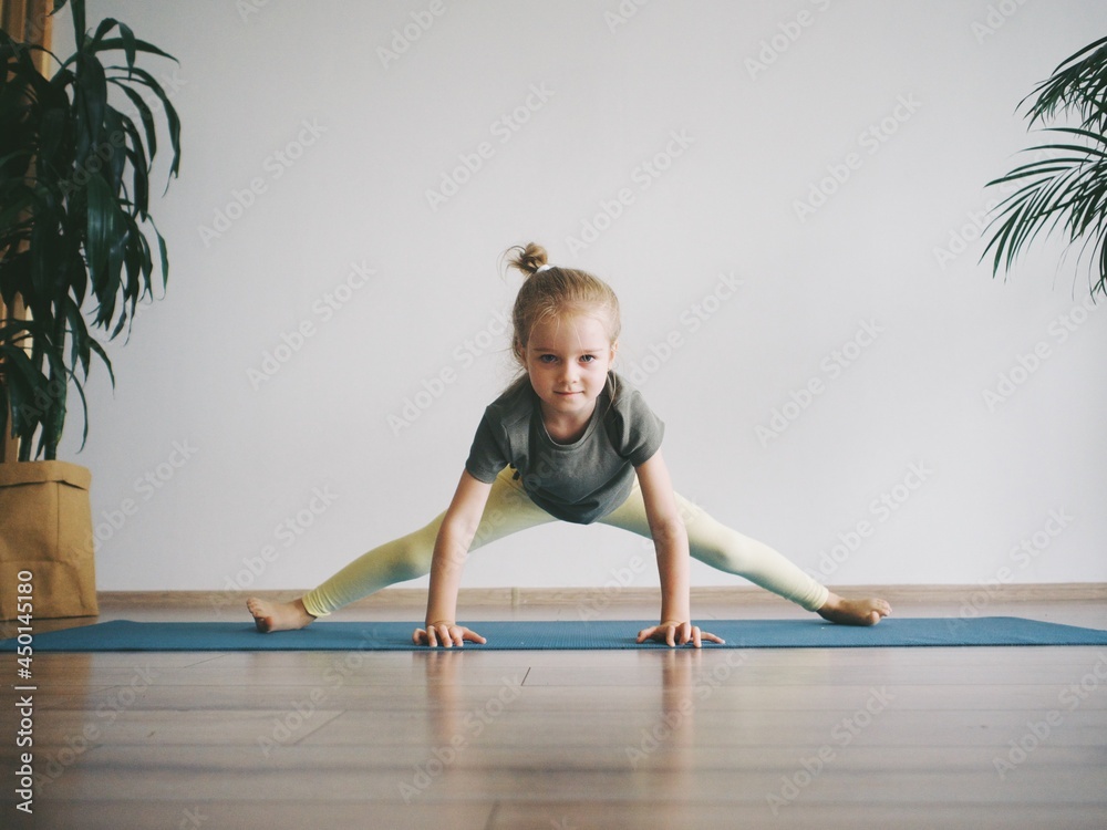 little girl is engaged in yoga, gymnastics, ballet on the rug. kids yoga little girl is engaged in yoga, gymnastics, ballet on the rug. kids yoga