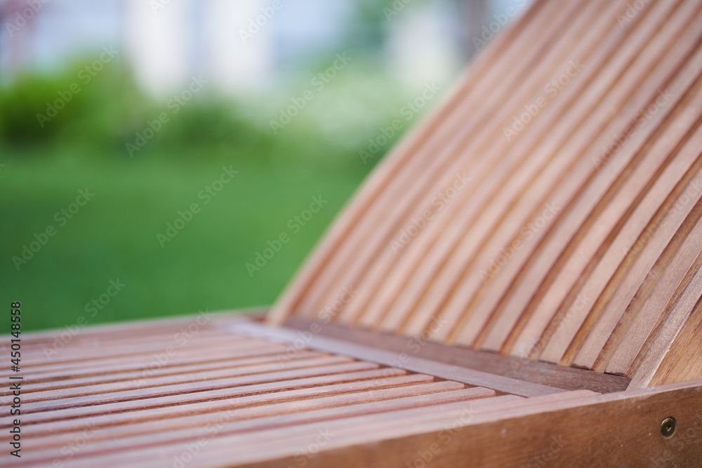 Close-up of a wooden chaise longue in a fresh garden on green grass.The concept of relaxation, tanning in the backyard. High quality photo Close-up of a wooden chaise longue in a fresh garden on green grass.The concept of relaxation, tanning in the backyard. High quality photo
