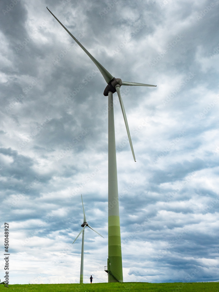 Contrast giant wind turbines and a boy at the foot of a pole. Contrast giant wind turbines and a boy at the foot of a pole.