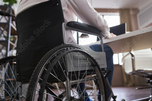 Close-up on a back side of a wheelchair and a businessman sitting in it