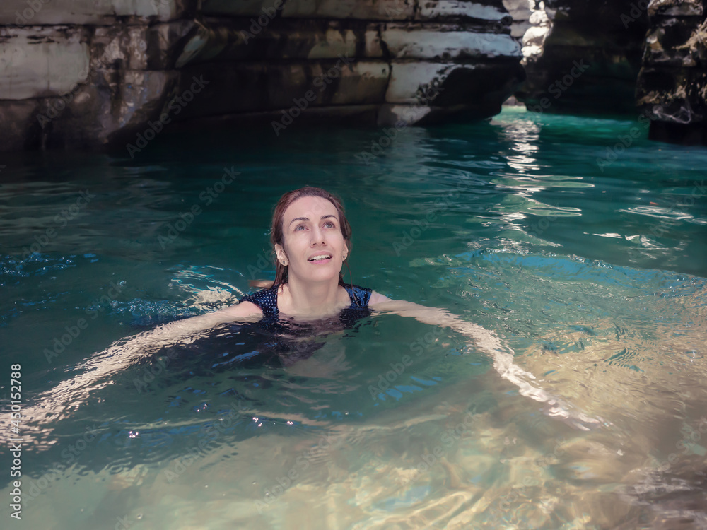 A girl swims in turquoise water in a shady gorge of canyons