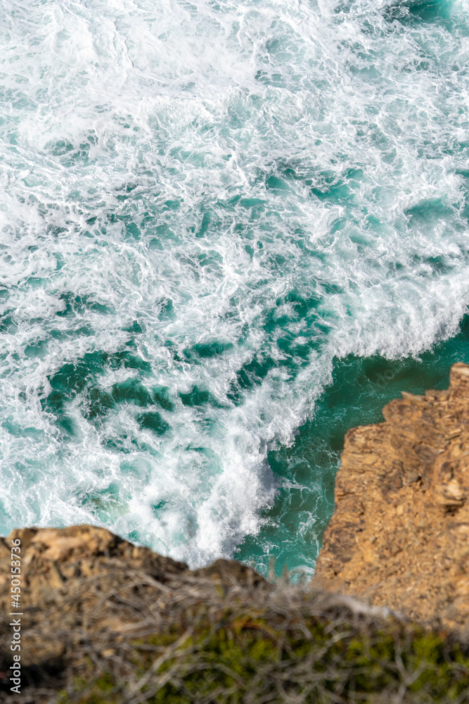 Aerial view of the ocean waves and cliff. Blue water background. Sea top view. Atlantic Ocean beach with sand texture	