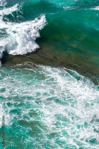 Aerial view of the ocean waves and cliff. Blue water background. Sea top view. Atlantic Ocean beach with sand texture 
