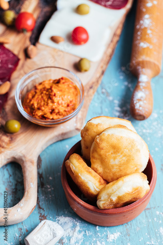 Fried dough called Ustipci with olives, paprika cream and meat served on a wooden board photo