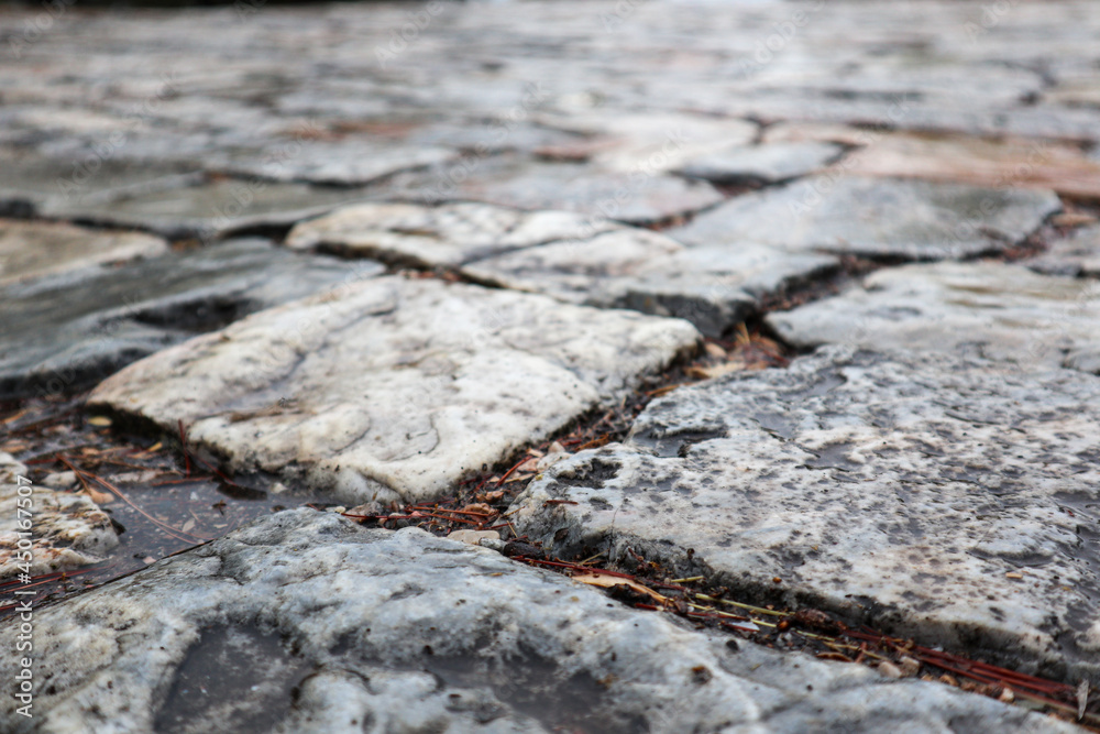 Ancient cobblestone pavement. Paving stone road close-up after rain. Summer travel Mediterranean historical landmarks Ancient cobblestone pavement. Paving stone road close-up after rain. Summer travel Mediterranean historical landmarks