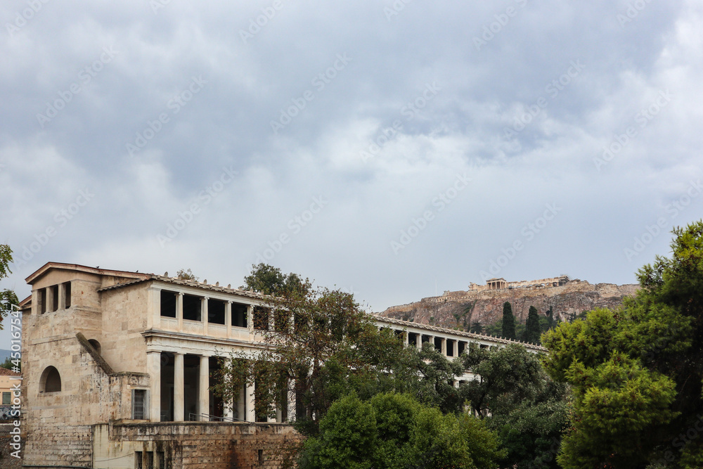 Stoa of Attalos in greenery, Athens old city center architecture on gray day with epic clouds and view on Acropolis hill