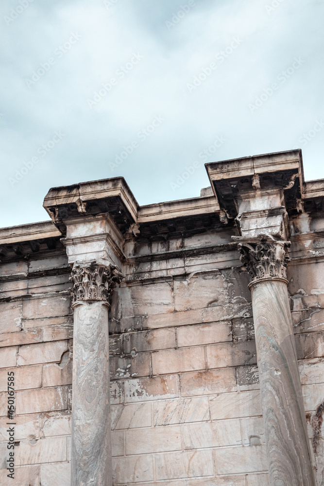 Hadrian's Library wall green marble Corinthian columns close-up. Ancient Greek colonnade architecture details in Athens, Greece. Vertical view on blue cloudy sky