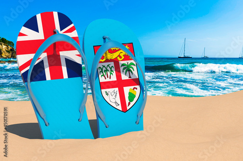Flip flops with Fijian flag on the beach. Fiji resorts, vacation, tours, travel packages concept. 3D rendering