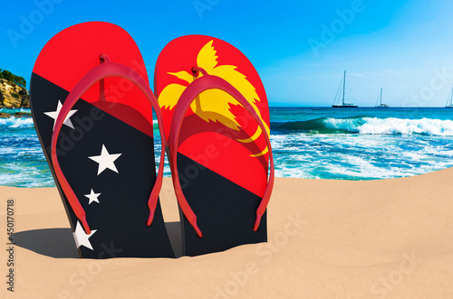 Flip flops with Papuan flag on the beach. Papua New Guinea resorts, vacation, tours, travel packages concept. 3D rendering