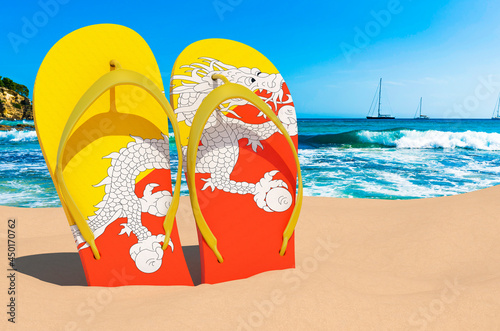 Flip flops with Bhutanese flag on the beach. Bhutan resorts, vacation, tours, travel packages concept. 3D rendering