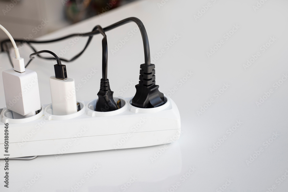 Electric white portable socket with connected devices on white table Electric white portable socket with connected devices on white table