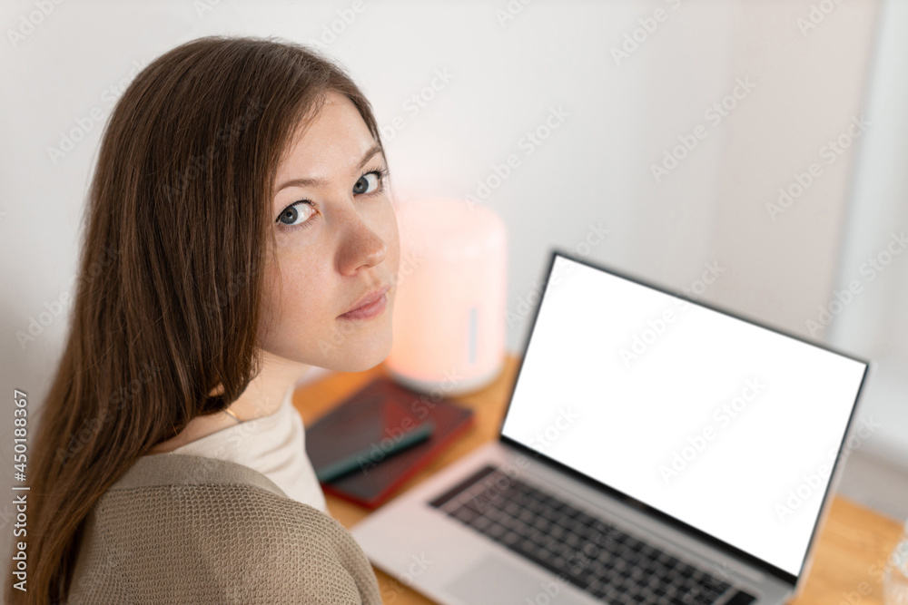 Pretty caucasian woman tired of working at computer. Working from home office. Attractive brunette woman looking into camera. Selective focus. On the background empty blank white screen. Pretty caucasian woman tired of working at computer. Working from home office. Attractive brunette woman looking into camera. Selective focus. On the background empty blank white screen.