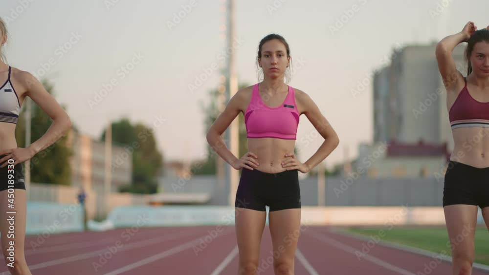 A group of women at the track and field competition warm up and prepare for the race. Concentrating on the start line at the stadium
