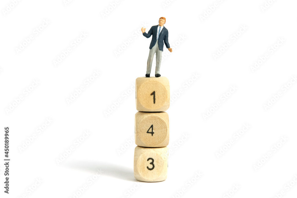 Miniature people toy figure photography. A shrugging businessman standing above wooden dice. Isolated on white background. Image photo Miniature people toy figure photography. A shrugging businessman standing above wooden dice. Isolated on white background. Image photo