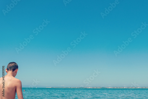 Rear of man standing on the beach. Sunny weather. Man alone with the sea