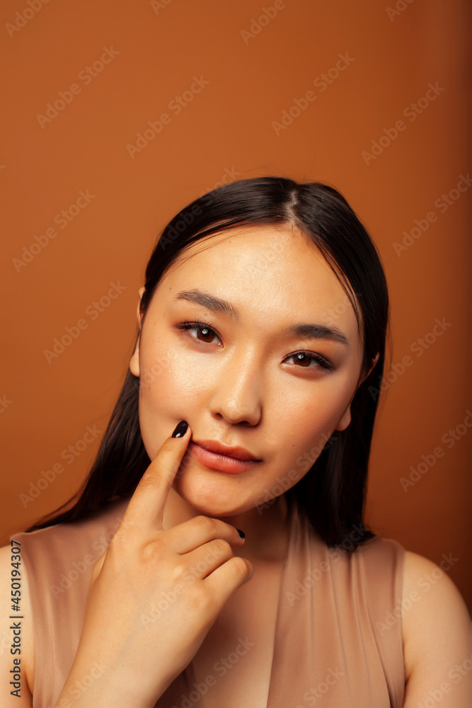 young pretty asian woman cheerful smiling posing on warm brown background, lifestyle people concept
