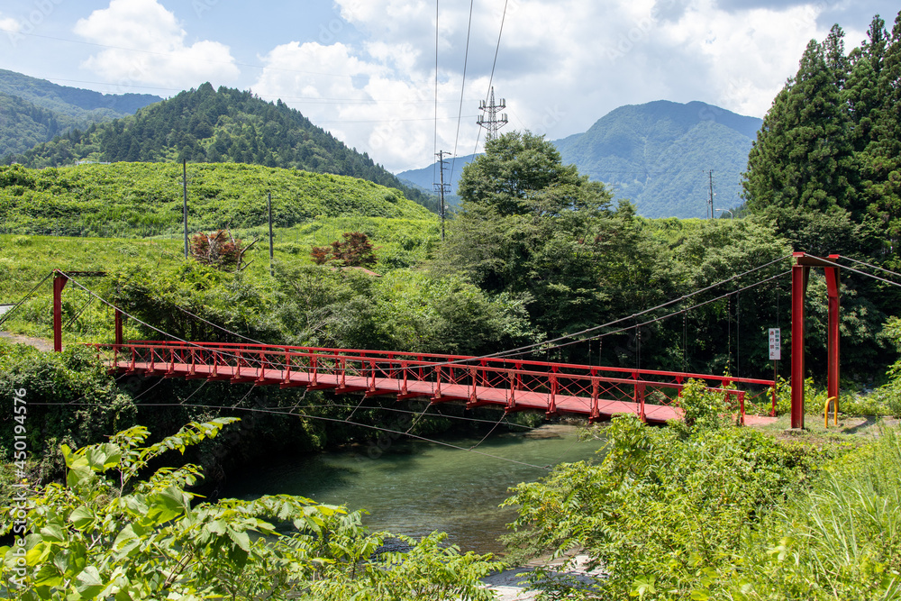 山間を流れる川に架けられた鉄製の赤い吊り橋