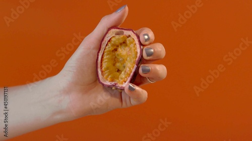 Studio photo of the hand of a woman who is showing a passion fruit