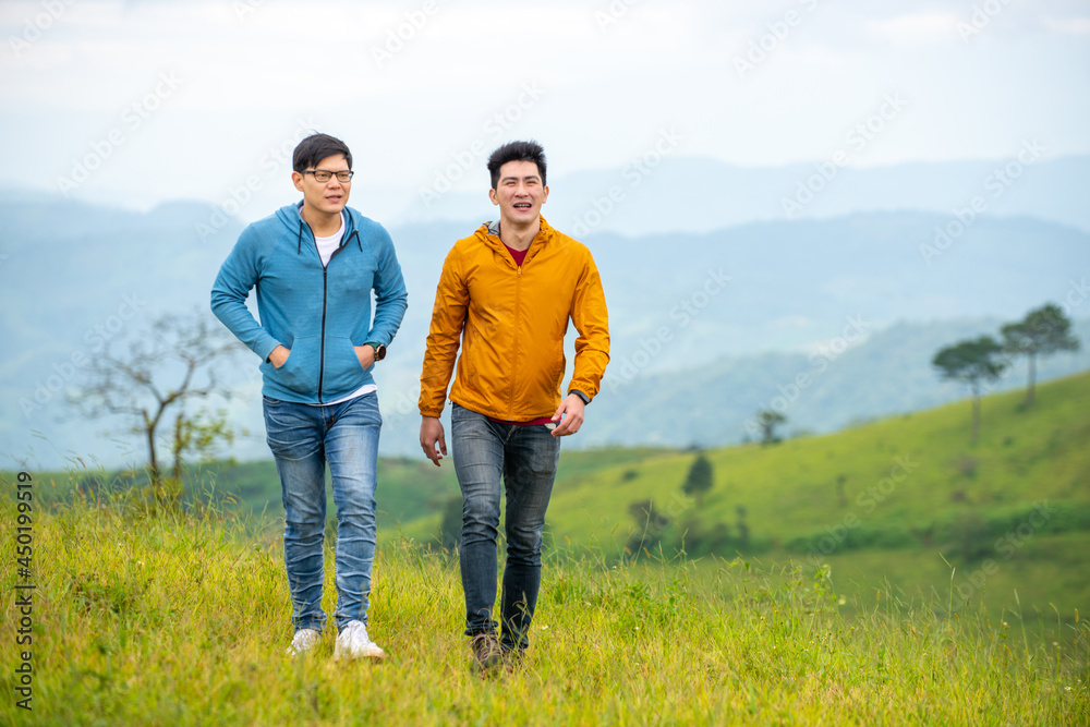 Two handsome Asian people man friends walking with talking together on mountain trail. Healthy male friendship enjoy outdoor activity and active lifestyle hiking and camping in summer vacation. Two handsome Asian people man friends walking with talking together on mountain trail. Healthy male friendship enjoy outdoor activity and active lifestyle hiking and camping in summer vacation.