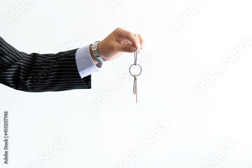 arm of a man in a suit holding some house keys on a white background