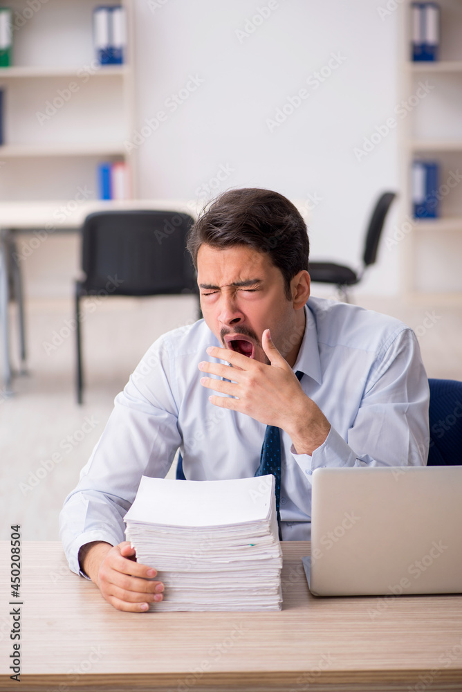 Naklejka premium Young male employee unhappy with excessive work in the office