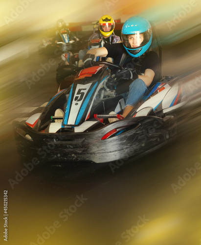 Glad man and women competing on racing cars at kart circuit