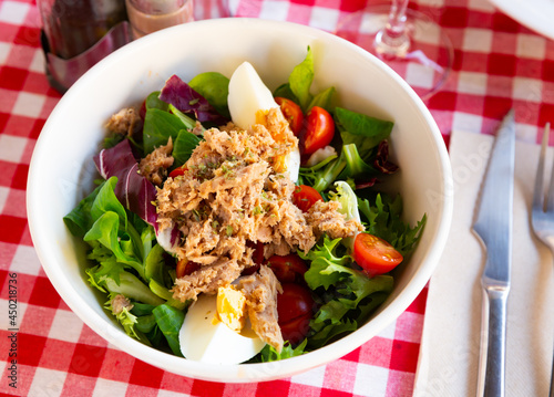 Portion of delicious salad with canned tuna fish, greens, eggs and cherry tomatoes
