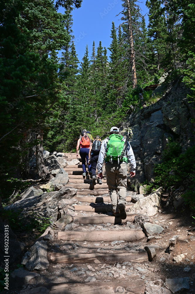 Young hikers ascend Emerald Lake Trail in Rocky Mountain National Park, Colorado on sunny summer morning.